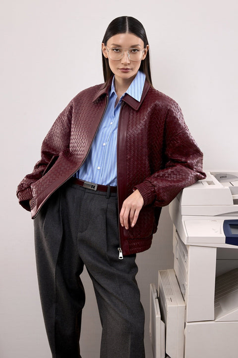 A woman models a deep burgundy bomber jacket with a softly structured silhouette, combining comfort and effortless style.