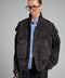 A woman wears a charcoal suede jacket crafted from soft, high-quality suede leather, featuring a flattering fit and rich hue for versatile style.